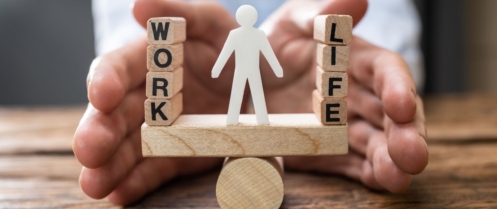 Work-Life-Balance: Ein Männchen steht in der Mitte auf einer Wippe, zwischen Work und Life.
