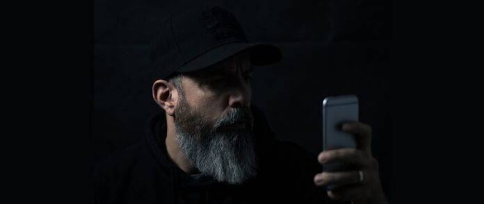Dark Social: Ein Mann im Dunkeln mit einem Smartphone in der Hand.