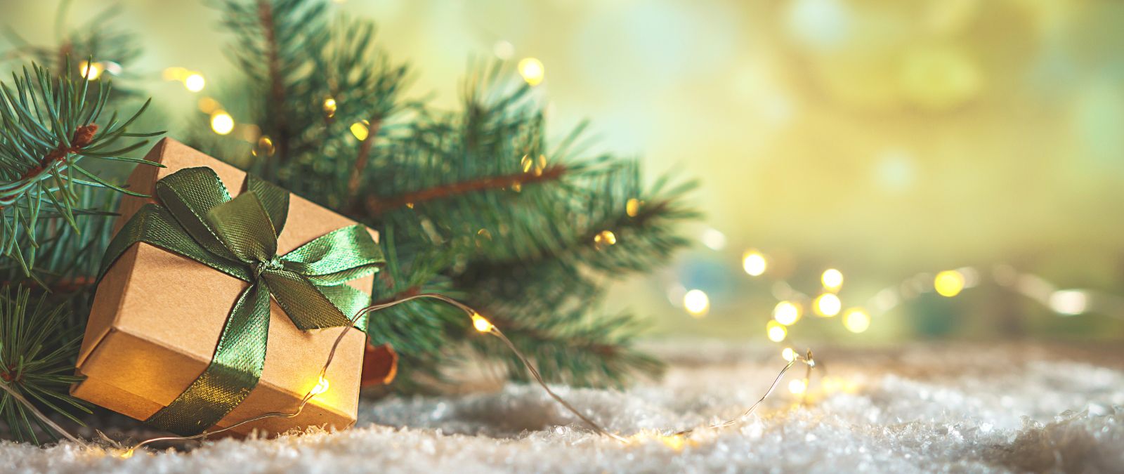 Last-Minute-Weihnachtsgeschenke: Ein Geschenk mit grüner Schleife vor einem Tannenzweig.