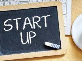 Startup: Auf einem Schreibtisch liegt eine Tafel mit der Aufschrift "Startup".