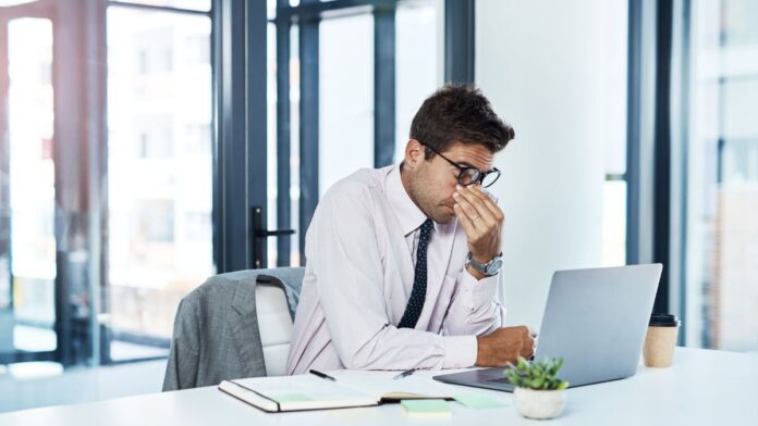 Fehlerquellen bei der Lohnsteuerprüfung: Ein Mann im Anzug sitzt frustriert vor seinem Laptop.