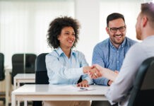 Recruiting: Personalvermittler und seine Klientin schließen ein Bewerbungsgespräch erfolgreich ab.