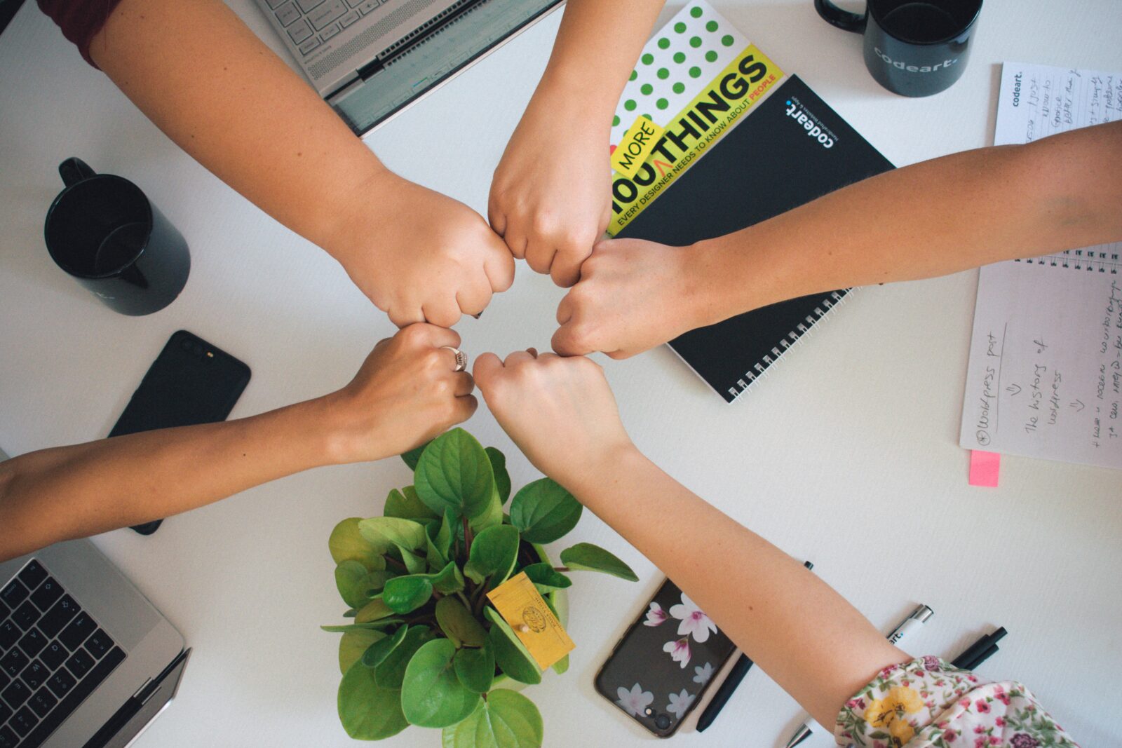Employer Branding: Mitarbeiter halten ihre Hand in die Mitte eines Tisches, um Verbundenheit und Teamwork auszudrücken - Employer Branding und warum du es nutzen solltest - Quelle: ©Antonio Janeski - unsplash.com
