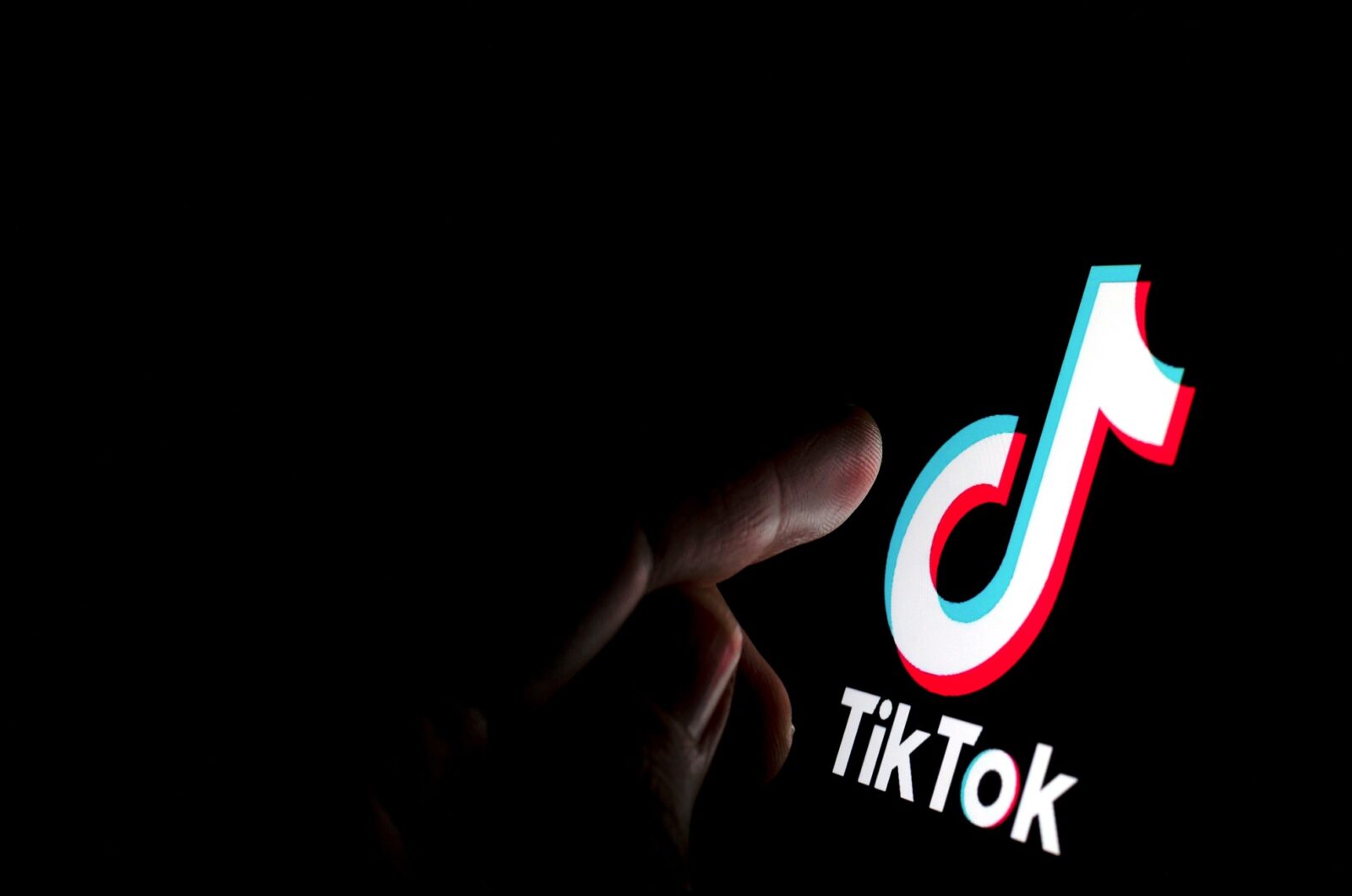 TikTok: Im schwarzen Hintergrund tippt ein Finger auf das TikTik-Logo.
