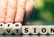 Vision: Eine Hand dreht Würfel und ändert das Wort Vision zu Mission.