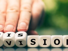 Vision: Eine Hand dreht Würfel und ändert das Wort Vision zu Mission.