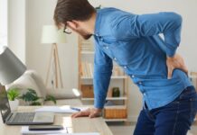 Rückenschmerzen: Ein Mann leidet an Rückenschmerzen am Arbeitsplatz.