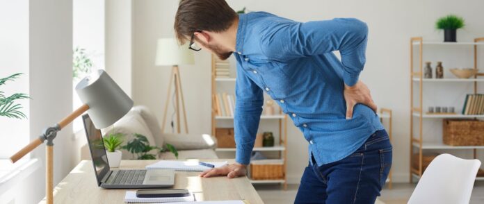 Rückenschmerzen: Ein Mann leidet an Rückenschmerzen am Arbeitsplatz.