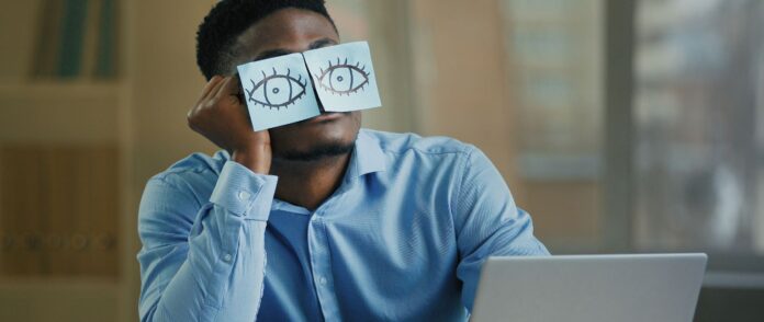 Fake Work: Ein Mann schläft hinter auf Papier gemalte Augen.