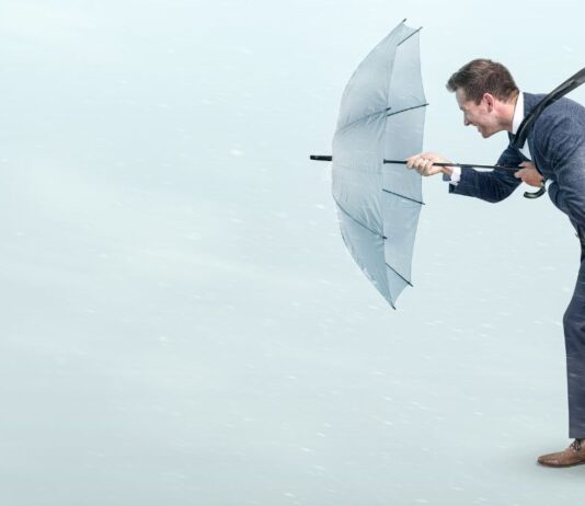 Schwierige Zeiten: Ein Mann im Anzug läuft mit einem Regenschirm, während eines Sturms.