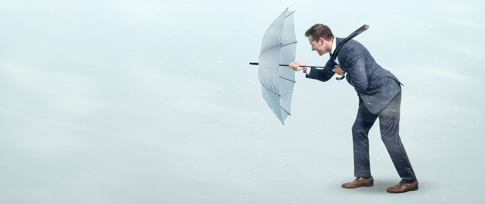 Schwierige Zeiten: Ein Mann im Anzug läuft mit einem Regenschirm, während eines Sturms.