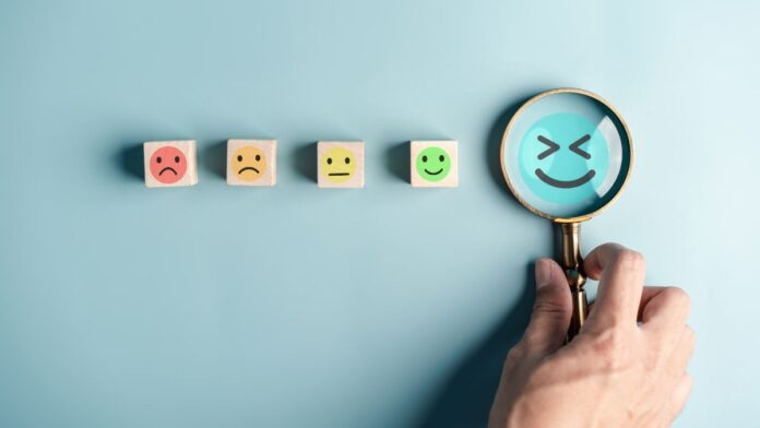 Positive Emotionen: Holzblöcke mit verschiedenen Emojis und einer Lupe.