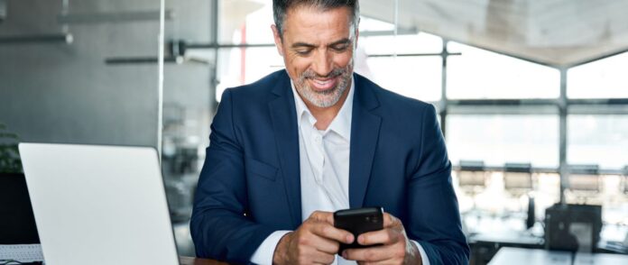 Ein Mann im Anzug schaut auf sein Smartphone.