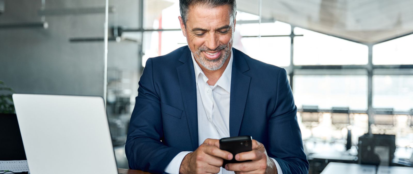 Ein Mann im Anzug schaut auf sein Smartphone.