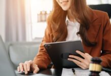 Smart Working: Eine Frau mit Tablet und Laptop arbeitet im Büro.