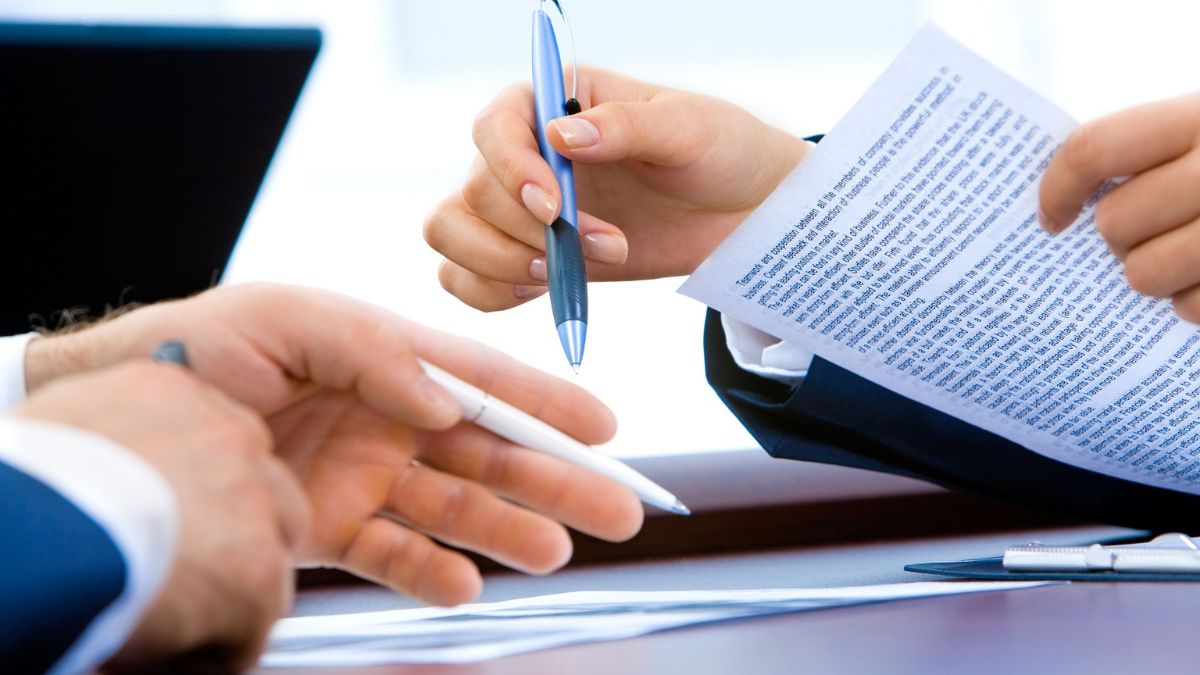 Personalberatung: Zwei Personen im Anzug halten Stift und Papier in den Händen.