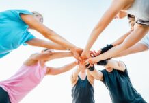 Teamoutfits: Eine Gruppe greift sich an den Händen.