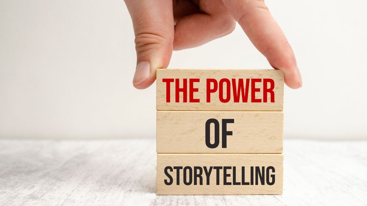 Die Macht des Storytellings in der Markenbildung: Eine Hand stapelt 3 Holzblöcke, auf denen "die Macht des Storytellings" stehen.