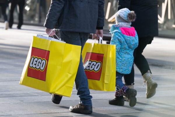 Ole Kirk Christiansen: Eine Familie läuft mit Lego-Tüten durch eine Einkaufszone