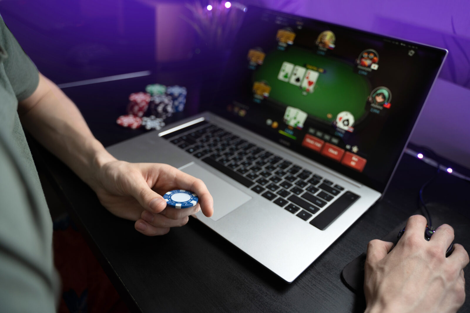 Person spielt bei einem Online-Casino, Blick auf Bildschirm, Hände und Poker-Chips