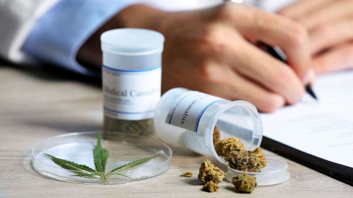 Medizinisches Cannabis: Ein Arzt schreibt auf ein Rezeptformular, vor ihm sind zwei Flaschen mit medizinischem Cannabis.
