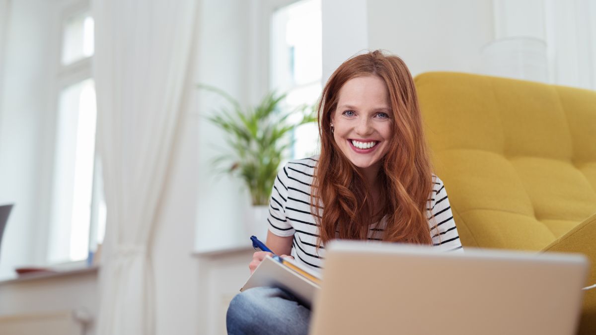 Weiterbildung: Eine glückliche Frau lernt zuhause am Laptop.