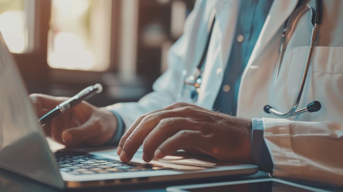 Betriebliche Krankenkasse: Nahaufnahme eines Arztes bei der Arbeit und beim Tippen auf einem Laptop.