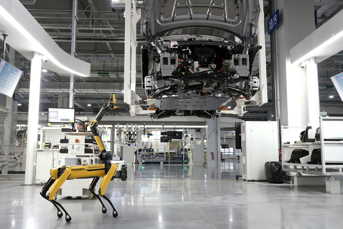 Roboter in Fertigungshalle, der ein Auto konstruiert.